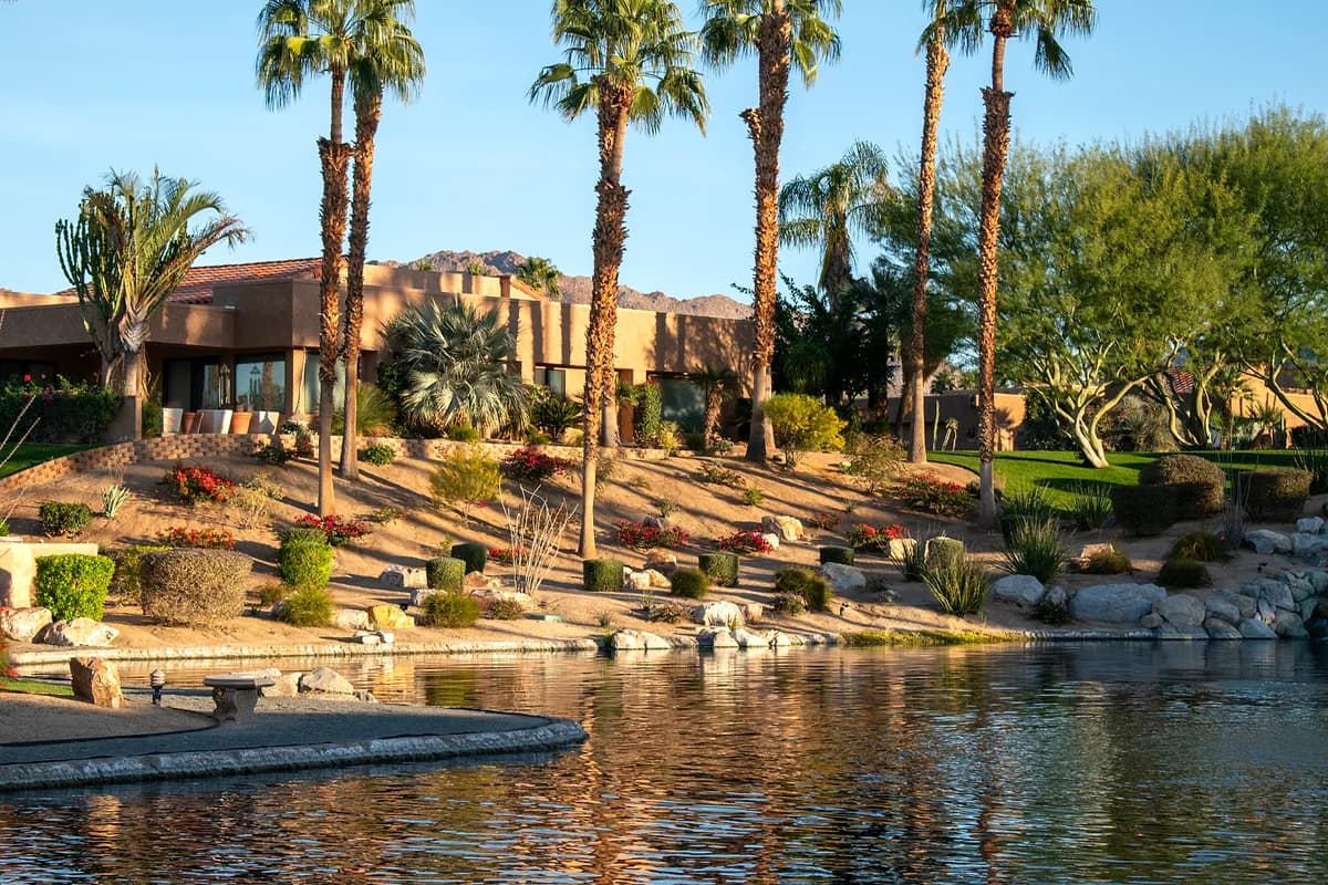 Lakefront home with palms and terraced landscape