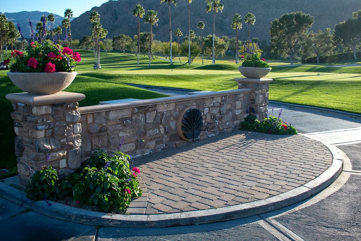 Stone entrance wall with flower urns and golf course